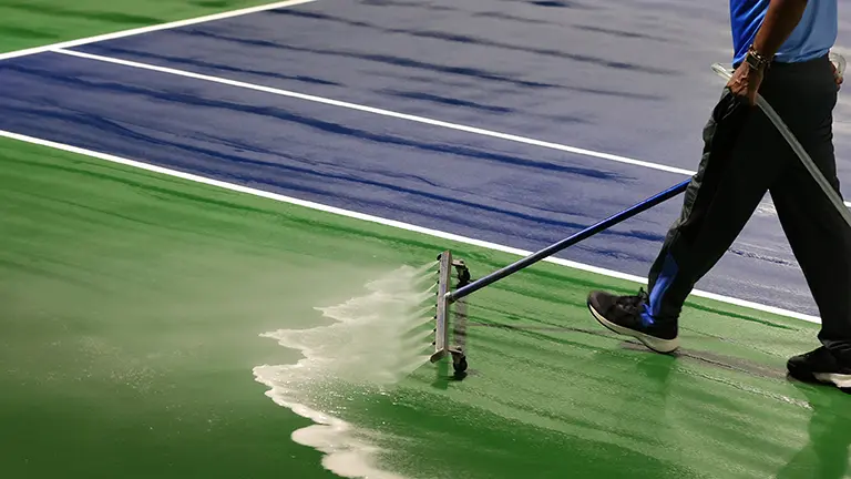 Worker cleaning tennis court